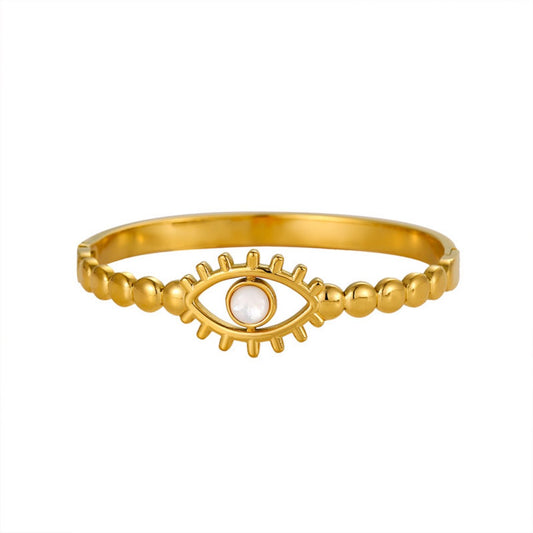 Gold open cuff bracelet with a white shell bead at the center of an evil eye design